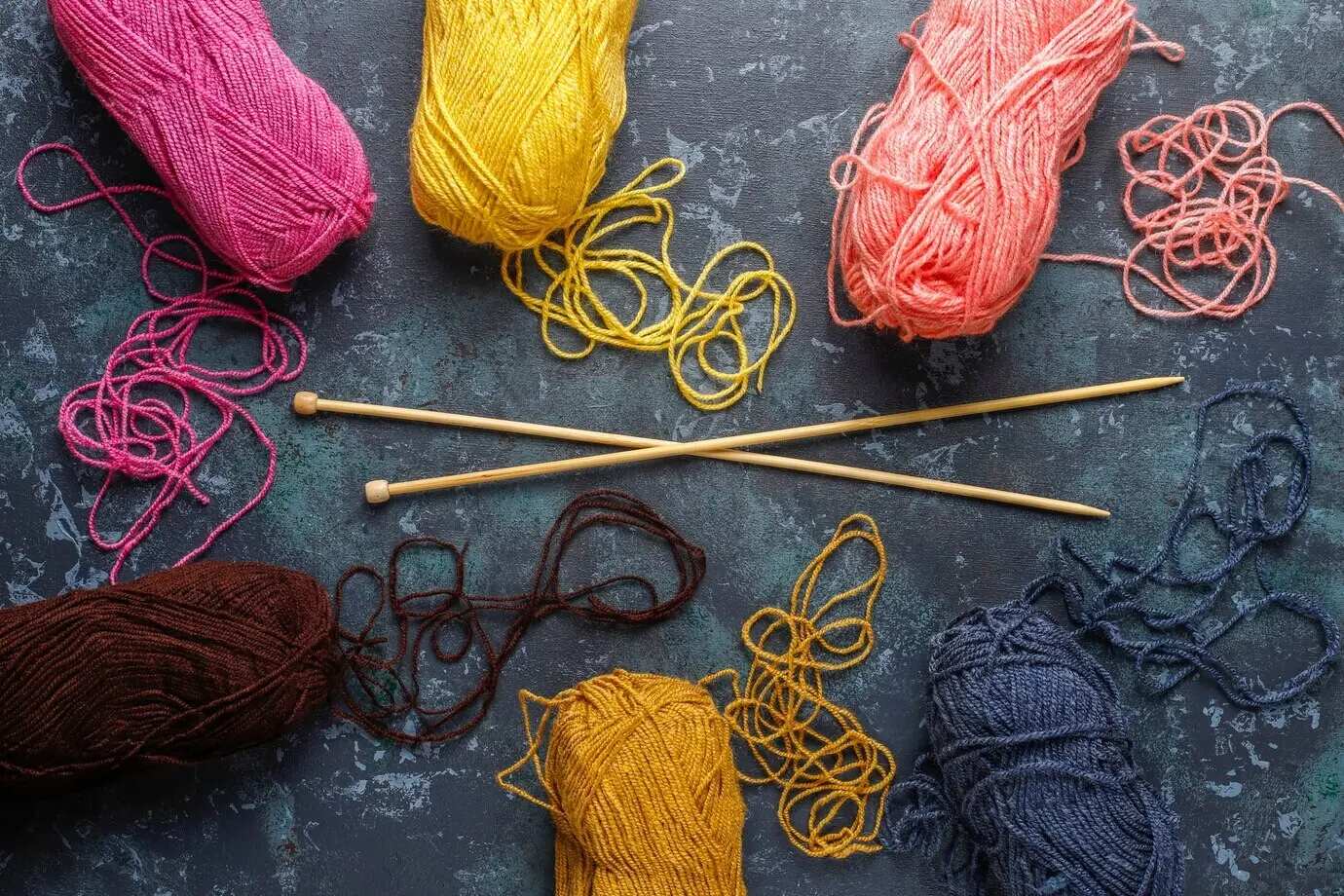 Garnknäuel in verschiedenen Farben mit Stricknadeln.